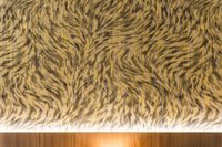 Texturierte schwarz-goldene Tierfellmusterwand mit Holzuntergrund