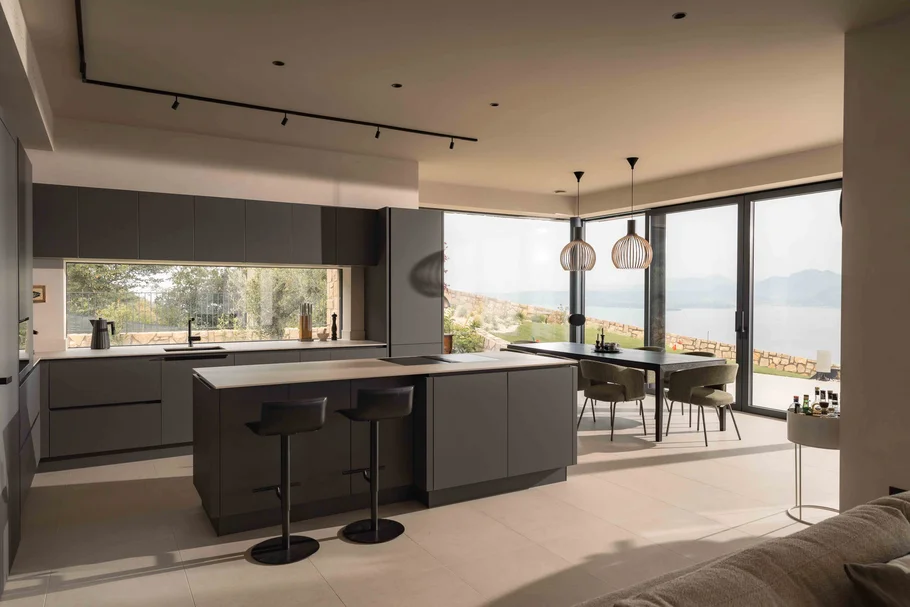 INTERIOS. Il tuo studio di interior design. Cucina moderna con isola, zona pranzo e vista sul lago dalle ampie finestre