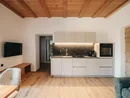 Cucina moderna con soffitto in legno, mobili bianchi e forno integrato