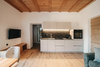 Moderne Küche mit Holzdecke, weißen Schränken und integriertem Backofen
