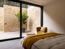 Schlafzimmer mit gelbem Sessel und Blick auf Zitronenbaum hinter Glaswand