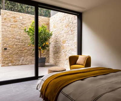 Camera da letto con poltrona gialla e vista su limoni dietro vetrata