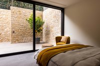 Schlafzimmer mit gelbem Sessel und Blick auf Zitronenbaum hinter Glaswand