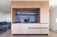 Minimalistische Küche mit Holzfronten, grauer Marmorwand und Kaffeemaschine