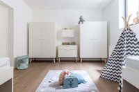 Helles Kinderzimmer mit weißen Schränken, Spielteppich und Zelt