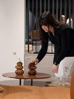 Donna sistema un vaso decorativo su un tavolino nel soggiorno