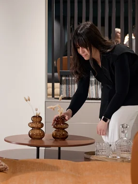 Frau arrangiert Dekorationsvase auf einem kleinen Tisch im Wohnzimmer