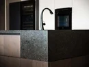 Moderne Kücheninsel mit schwarzem Wasserhahn und dunkler Steinplatte