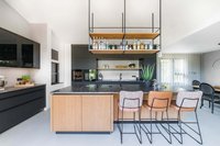 Moderne Küche mit Kücheninsel, Barhockern und hängendem Regal mit Flaschen