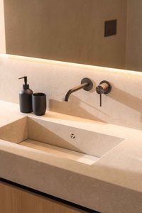 Modernes Waschbecken mit schwarzem Seifenspender und wandmontiertem Wasserhahn