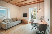 Wohnzimmer mit grau Sofa, Holztisch, Sesseln und Holzbalkendecke