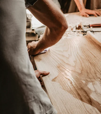 Handwerker bearbeiten ein Holzbrett in einer Werkstatt