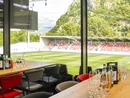 Blick von einem VIP-Bereich auf ein Fußballstadion und grüne Berge