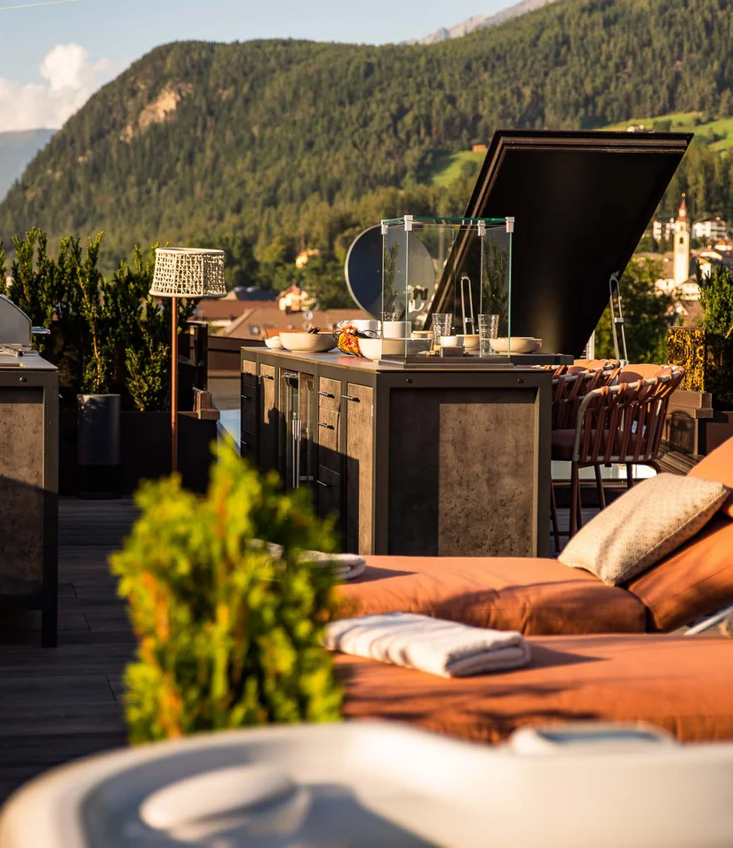 Sonnige Dachterrasse mit Liegestühlen, Außengrill und Bergblick