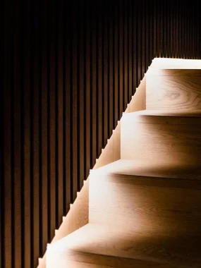Scala in legno scuro con illuminazione integrata sul muro