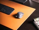 Schreibtisch mit Computermaus, Tastatur und orangefarbenem Schreibunterlage