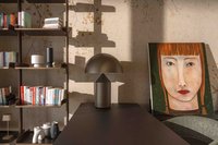 Wohnzimmer mit Bücherregal, Tischlampe und Porträt einer Frau