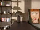 INTERIOS. Il tuo studio di interior design. Soggiorno con libreria, lampada da tavolo e ritratto di una donna