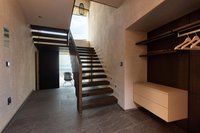 Moderner Innenraum mit Holztreppe und offenem Eingang zu Terrasse mit Stuhl