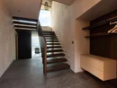 Moderner Innenraum mit Holztreppe und offenem Eingang zu Terrasse mit Stuhl