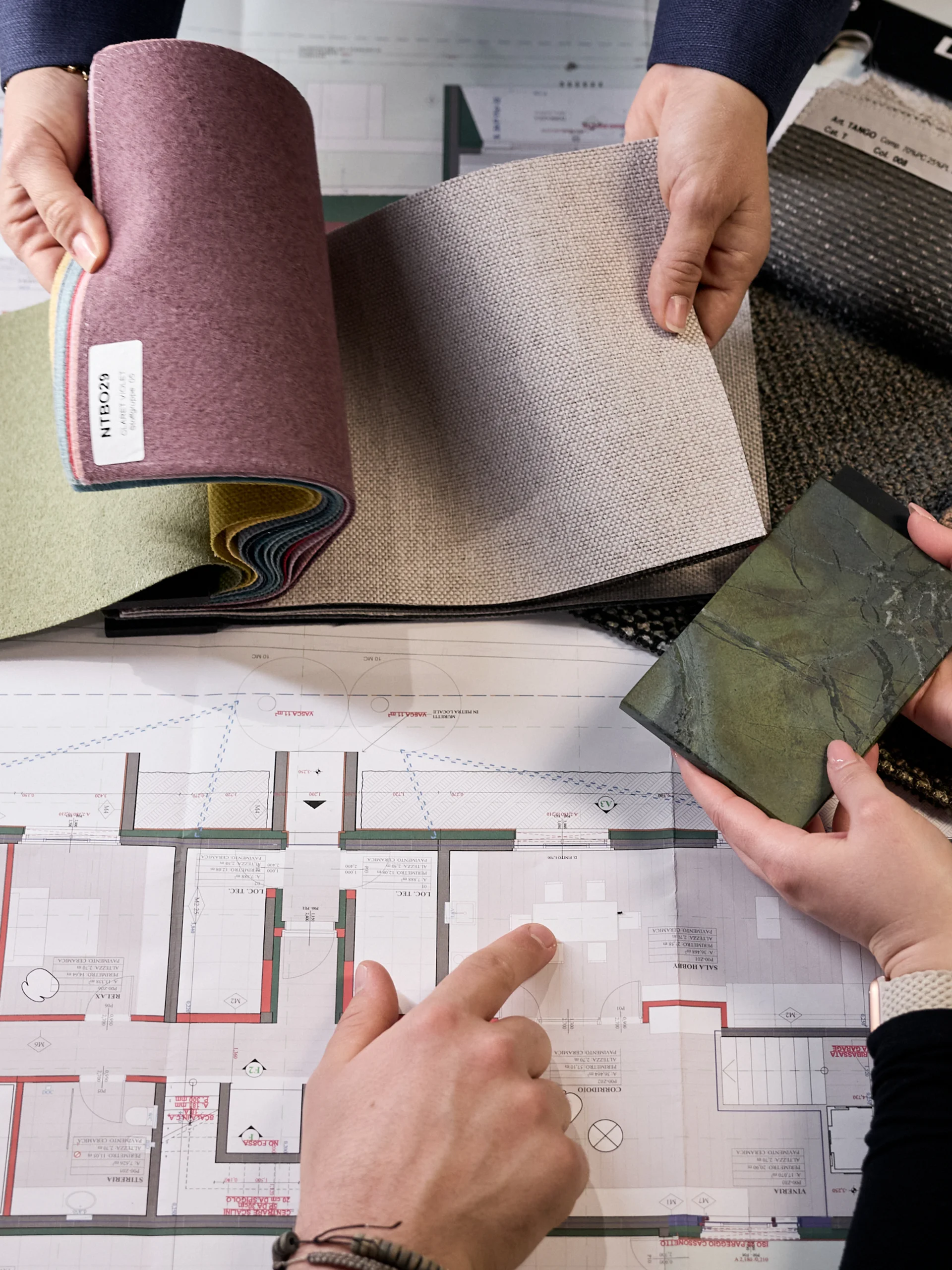 Personen vergleichen Stoffmuster auf einem architektonischen Bauplan
