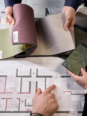 Personen vergleichen Stoffmuster auf einem architektonischen Bauplan