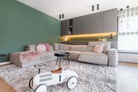 Modernes Wohnzimmer mit grauem Ecksofa, grünem Wandakzent und Kinderspielzeug-Auto