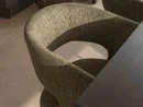 INTERIOS. Il tuo studio di interior design. Sedia imbottita accanto a un tavolo e a un vaso decorativo