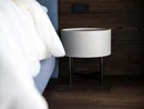 Moderner weißer Nachttisch neben einem blauen Bett vor dunkler Holzwand