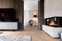 Moderner Wohnraum mit Kamin, Fernseher und gemütlichem Sessel neben Stehlampe