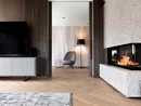 Moderner Wohnraum mit Kamin, Fernseher und gemütlichem Sessel neben Stehlampe