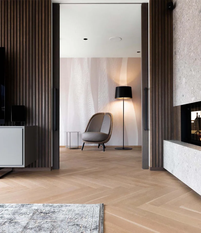 Moderner Wohnraum mit Kamin, Fernseher und gemütlichem Sessel neben Stehlampe