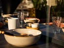 Tisch mit Keramikgeschirr und Gläsern im Sonnenlicht
