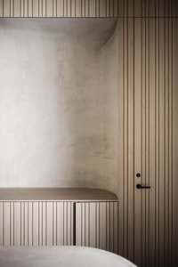 Minimalistische Holzschrankwand mit integriertem rundem Betonregal und schwarzem Türgriff