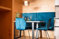 Moderner Essbereich mit blauen Stühlen und Bank vor Holzpaneelen