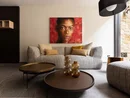 Modernes Wohnzimmer mit grauem Sofa, braunen Tischen und Porträt an roter Wand
