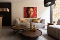 Modernes Wohnzimmer mit grauem Sofa, braunen Tischen und Porträt an roter Wand