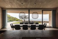 Moderner Essbereich mit großem Tisch vor Glaswand und Blick auf Terrasse und Natur