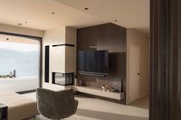 Modernes Wohnzimmer mit Kamin, Fernseher und Blick auf einen See und Berge