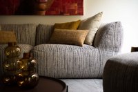 Gemütliches graues Sofa mit bunten Kissen und dekorativen Glaskaraffen auf Tisch