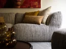 Gemütliches graues Sofa mit bunten Kissen und dekorativen Glaskaraffen auf Tisch
