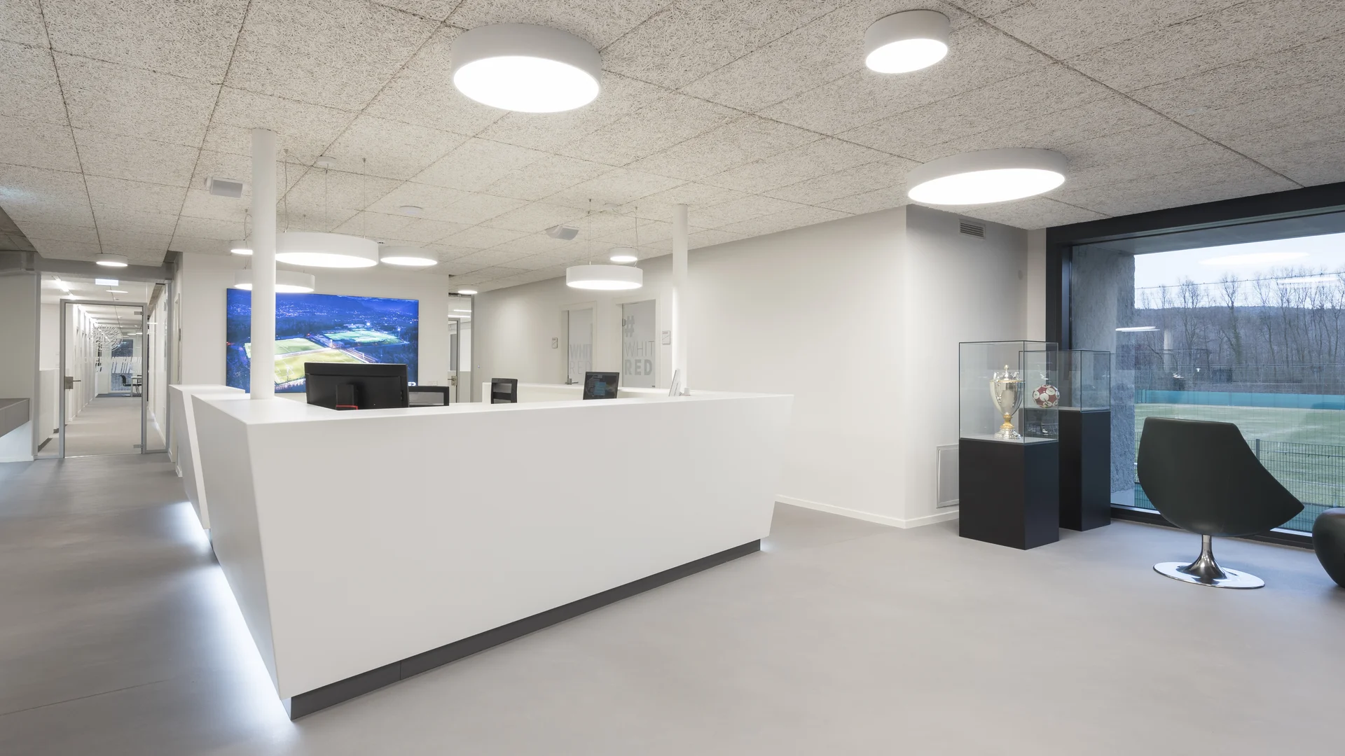 Moderner heller Empfangsbereich mit weißem Tresen und runden Deckenlampen