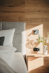 Helles Holztisch mit Vase, Lampe und Sofa mit Kissen im Sonnenlicht
