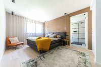 Modernes Schlafzimmer mit grauem Bett, gelber Decke und angrenzendem Bad
