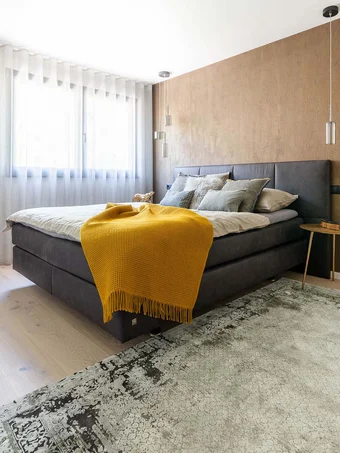 Modernes Schlafzimmer mit grauem Bett, gelber Decke und angrenzendem Bad