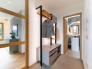 Moderner Flur mit Garderobe und Blick ins Badezimmer mit rundem Spiegel