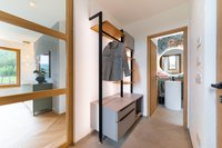Moderner Flur mit Garderobe und Blick ins Badezimmer mit rundem Spiegel