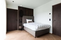Modernes Schlafzimmer mit Einzelbett, dunklen Holztüren und hellem Parkettboden