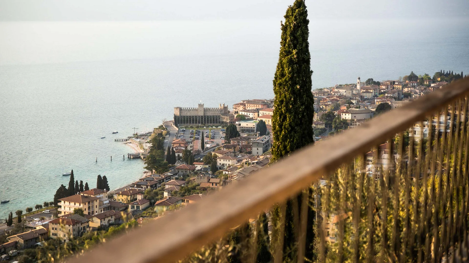 Blick auf den Gardasee und das Städtchen mit hoher Zypresse im Vordergrund