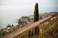 Blick auf den Gardasee und das Städtchen mit hoher Zypresse im Vordergrund